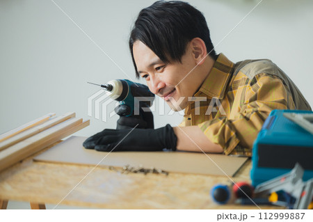 電動ドライバーで作業する若い男性 電動ドライバーで作業する若い男性 112999887