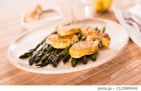 Fried chicken breast pieces with asparagus on white plate Fried chicken breast pieces with asparagus on white plate 112999948