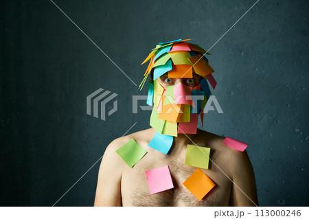 Shocked amazed man with colorful sticky notes all over his face and body 113000246
