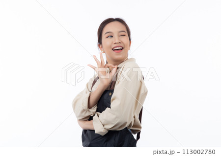 Portrait smiling young asian woman wearing apron showing ok sign with hand isolated. Portrait smiling young asian woman wearing apron showing ok sign with hand isolated. 113002780