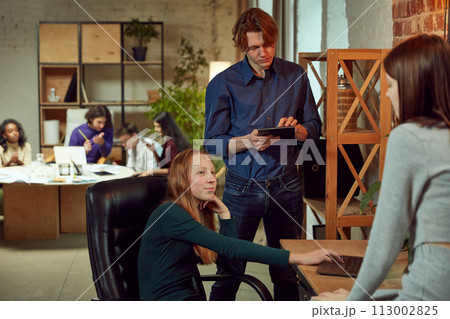 Students are studying in library. Young people are spending time together. Reading book, working with laptop and communicating 113002825