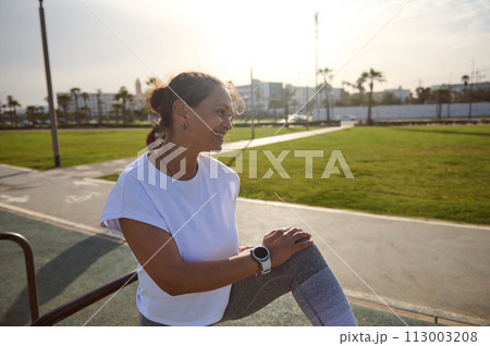 Female athlete resting after workout on sportsground, smiling looking aside. Sport Fitness Active Healthy lifestyle 113003208