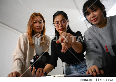 Group of young creative people working together in studio during photo session Group of young creative people working together in studio during photo session 113003458