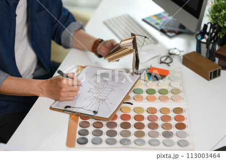 Experienced interior designer working with material and color samples at his workplace Experienced interior designer working with material and color samples at his workplace 113003464
