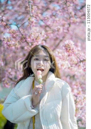 桜の下でお団子を食べる女性 113004072