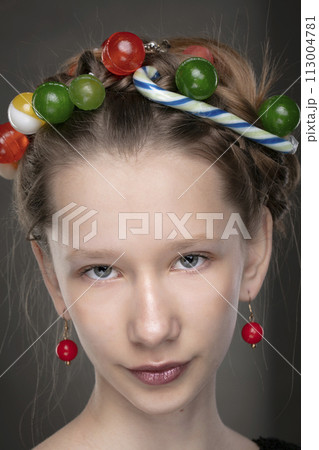Portrait of a funny teenage girl with a wreath of sweets on her head. 113004781