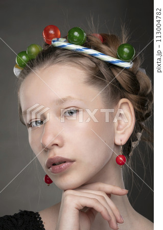 Portrait of a funny teenage girl with a wreath of sweets on her head. Portrait of a funny teenage girl with a wreath of sweets on her head. 113004782