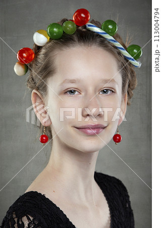 Portrait of a funny teenage girl with a wreath of sweets on her head. Portrait of a funny teenage girl with a wreath of sweets on her head. 113004794
