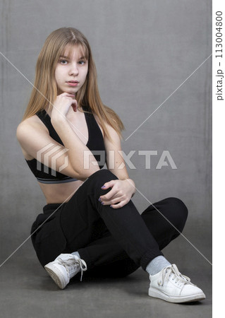 Plain teenage girl in sportswear on a gray background. Plain teenage girl in sportswear on a gray background. 113004800