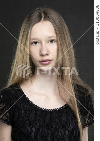 Beautiful teenager girl with long hair on a gray background. A girl with a European face type. Beautiful teenager girl with long hair on a gray background. A girl with a European face type. 113004806