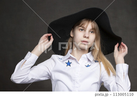 Happy teenage girl in white shirt and black hat is shot against a gray background. Happy teenage girl in white shirt and black hat is shot against a gray background. 113005110