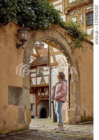 Winter Fun in Bitigheim-Bissingen: Beautiful Girl in Pink Jacket Amidst Half-Timbered Charm. a lovely girl in a pink winter jacket standing in the archway of the historic town of Bitigheim-Bissingen Winter Fun in Bitigheim-Bissingen: Beautiful Girl in Pink Jacket Amidst Half-Timbered Charm. a lovely girl in a pink winter jacket standing in the archway of the historic town of Bitigheim-Bissingen 113005282