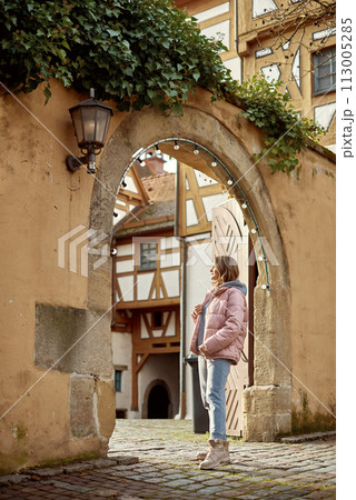 Winter Fun in Bitigheim-Bissingen: Beautiful Girl in Pink Jacket Amidst Half-Timbered Charm. a lovely girl in a pink winter jacket standing in the archway of the historic town of Bitigheim-Bissingen 113005285