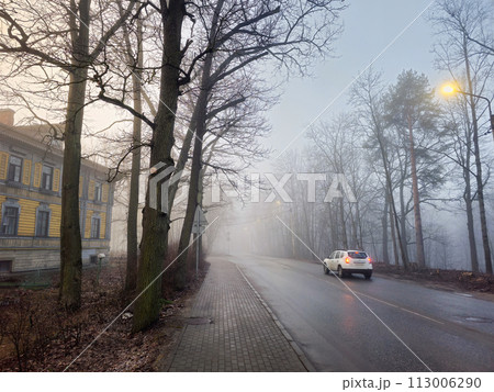 car on the move with its lights on a foggy city road 113006290