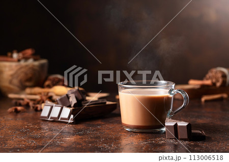 Glass of cocoa drink and pieces of dark chocolate on a brown vintage table. Glass of cocoa drink and pieces of dark chocolate on a brown vintage table. 113006518