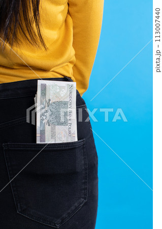 The woman is holding a bundle of 100 Polish zlotys banknotes in her back pocket. 113007440