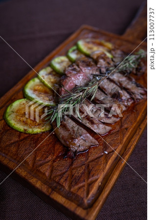 Beef steak with grilled zucchini on a wooden board 113007737