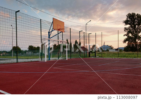 Outdoors mini football and basketball court with ball gate and basket surrounded with high protective fence. Outdoors mini football and basketball court with ball gate and basket surrounded with high protective fence. 113008097