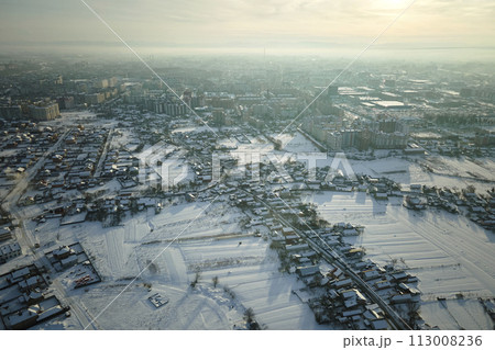 Aerial view of private homes with snow covered roofs in rural suburbs town area in cold winter Aerial view of private homes with snow covered roofs in rural suburbs town area in cold winter 113008236