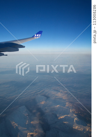 COPENHAGEN, DENMARK - 24 NOV 2018: Aeroplane window view with plane wing flying over the icebergs of Greenland at sunset with aerial perspective COPENHAGEN, DENMARK - 24 NOV 2018: Aeroplane window view with plane wing flying over the icebergs of Greenland at sunset with aerial perspective 113008286