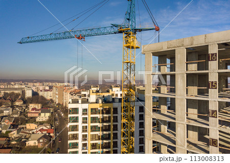 Aerial view of concrete frame of tall apartment building under construction in a city. 113008313