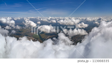 Aerial view from airplane window at high altitude of earth covered with white puffy cumulus clouds. Aerial view from airplane window at high altitude of earth covered with white puffy cumulus clouds. 113008335