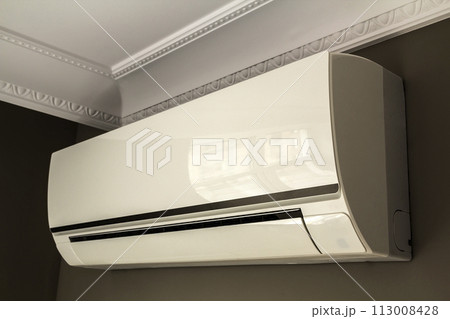 Cool air conditioner system on dark wall in room interior 113008428