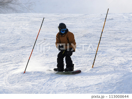 Snowboarder skiing between poles on a mountain Snowboarder skiing between poles on a mountain 113008644