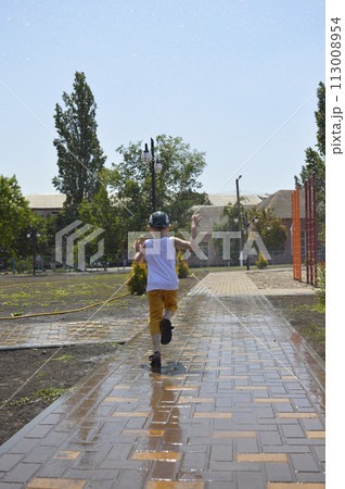 a boy runs through splashes of water on a hot summer day a boy runs through splashes of water on a hot summer day 113008954