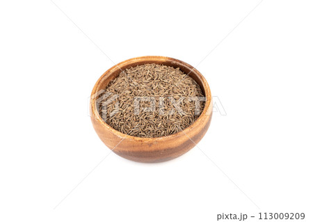 Aromatic cumin seeds in a wooden bowl on a white background. 113009209