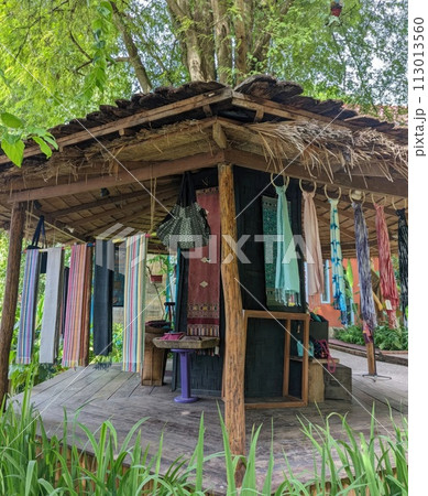 Thai wooden house in the garden with colorful cloth hanging on the wall Thai wooden house in the garden with colorful cloth hanging on the wall 113013560