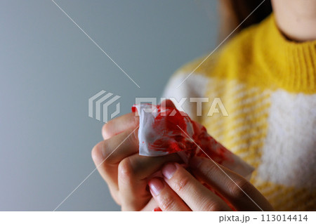血の付いたティッシュを持つ女性の手 113014414
