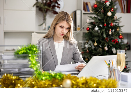 Female office worker doing paperwork during Christmastime Female office worker doing paperwork during Christmastime 113015575
