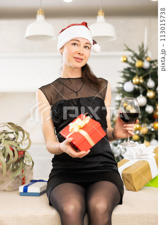 girl holds box with gift and glass of wine. She dreams of new year holiday. 113015738