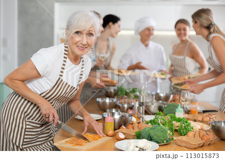 Elderly woman cooks chicken at master class 113015873