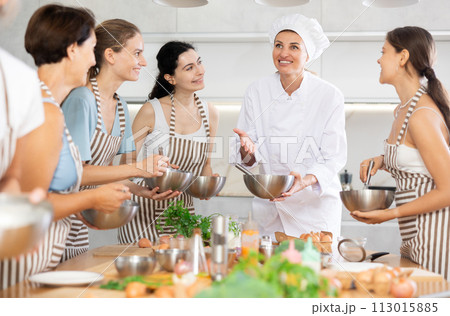 Young female cook holding bowl and whisk Young female cook holding bowl and whisk 113015885