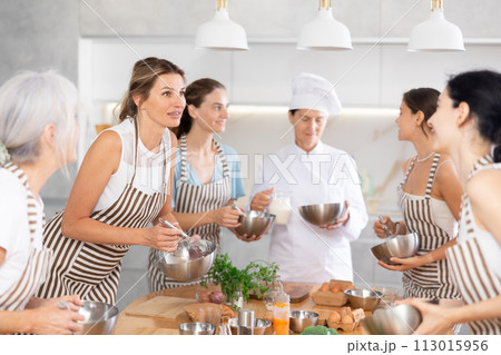 Young woman holding bowl and talking to other members Young woman holding bowl and talking to other members 113015956