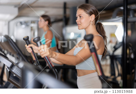 Sporty girl working out on elliptical machine in gym. Healthy active lifestyle concept 113015988