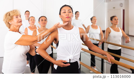 Dancing Asian woman standing in a ballet stance, where the choreographer helps to perform the exercise 113016000