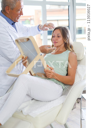 Elderly man doctor examining adult woman patient 113016027