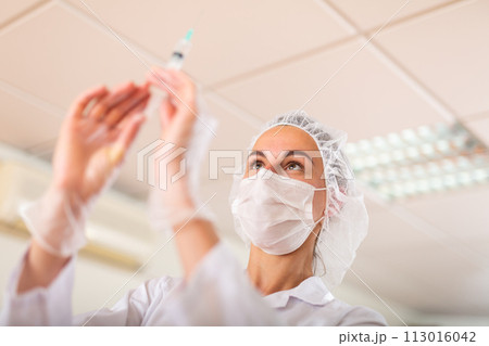 Nurse prepares a syringe for injection 113016042