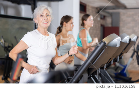 Elderly woman exercising on treadmill in gym Elderly woman exercising on treadmill in gym 113016159