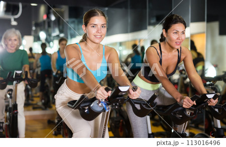 Two women warming up on bikes in gym 113016496