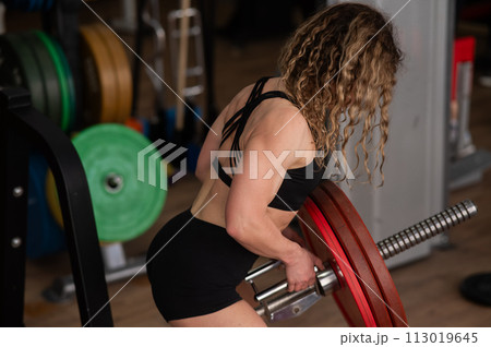 Middle-aged woman doing abdominal rows on a machine in the gym.  113019645