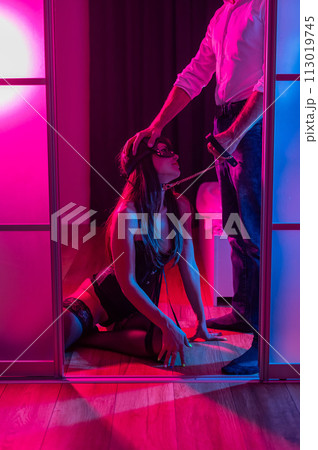 A woman is kneeling in front of a man. BDSM sex concept. Vertical photo.  113019745