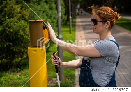 Blind woman pressing a button for a traffic light. Blind woman pressing a button for a traffic light. 113019767