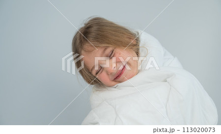 Portrait of a cute little girl wrapped in a white blanket. Portrait of a cute little girl wrapped in a white blanket. 113020073