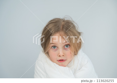 Portrait of a cute little girl wrapped in a white blanket. Portrait of a cute little girl wrapped in a white blanket. 113020255