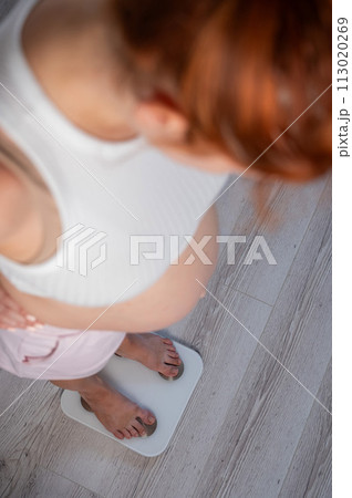A pregnant woman stands on the scales and controls her weight. A pregnant woman stands on the scales and controls her weight. 113020269