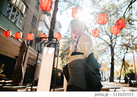 Portrait of an Asian woman against the background of Chinese lanterns outdoors.  113020353